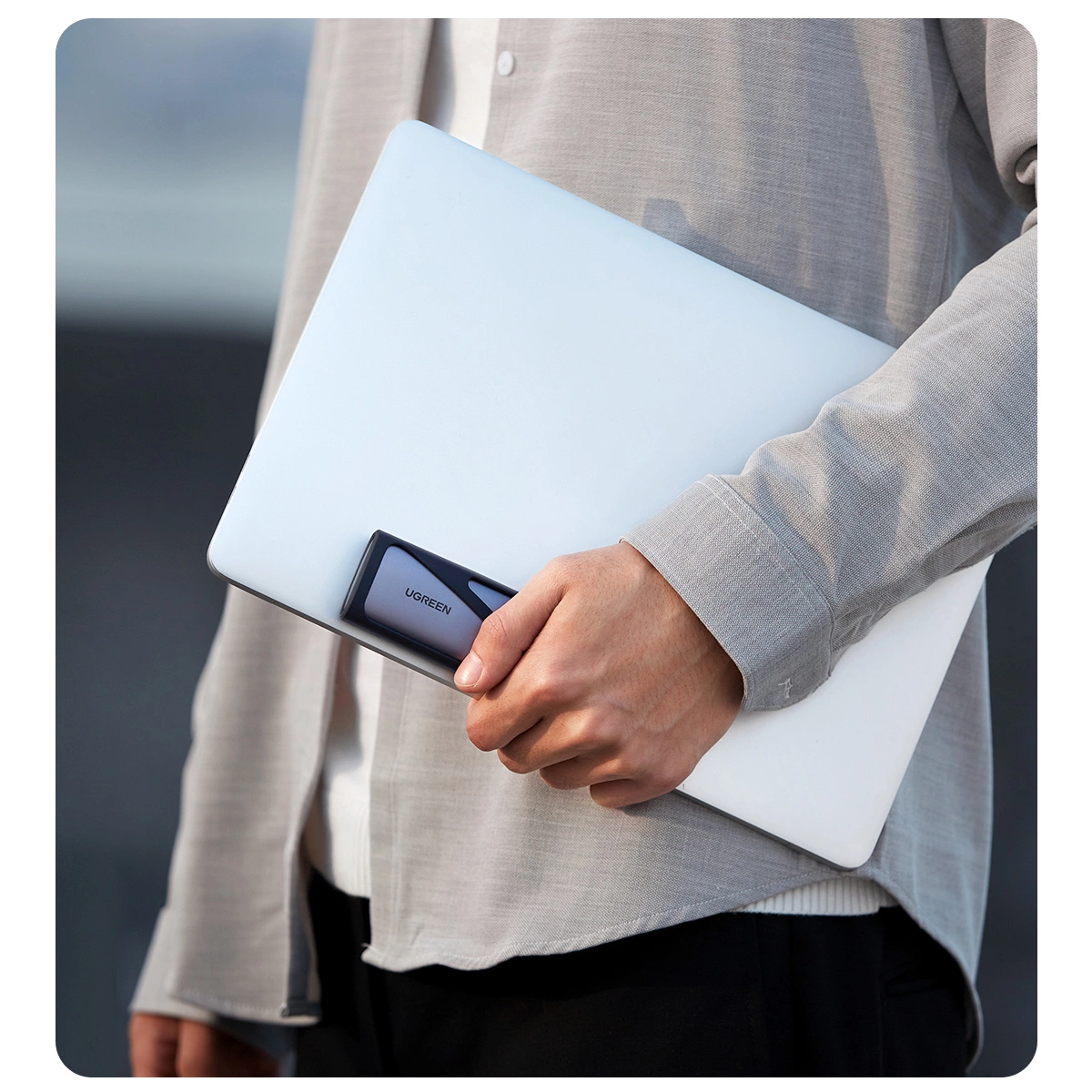 The man holds a Ugreen drive tray along with a laptop in his hand