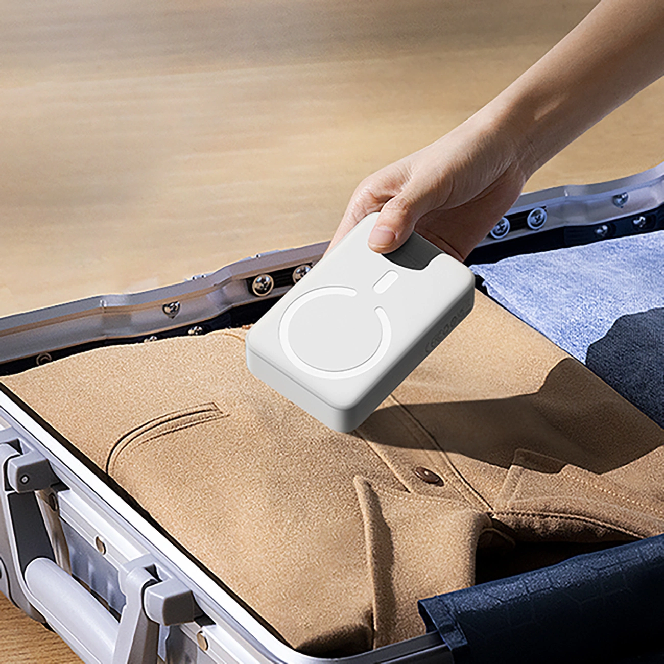 A person puts the Baseus Magnetic Mini Induction Powerbank 10000mAh 30W into a suitcase with clothes