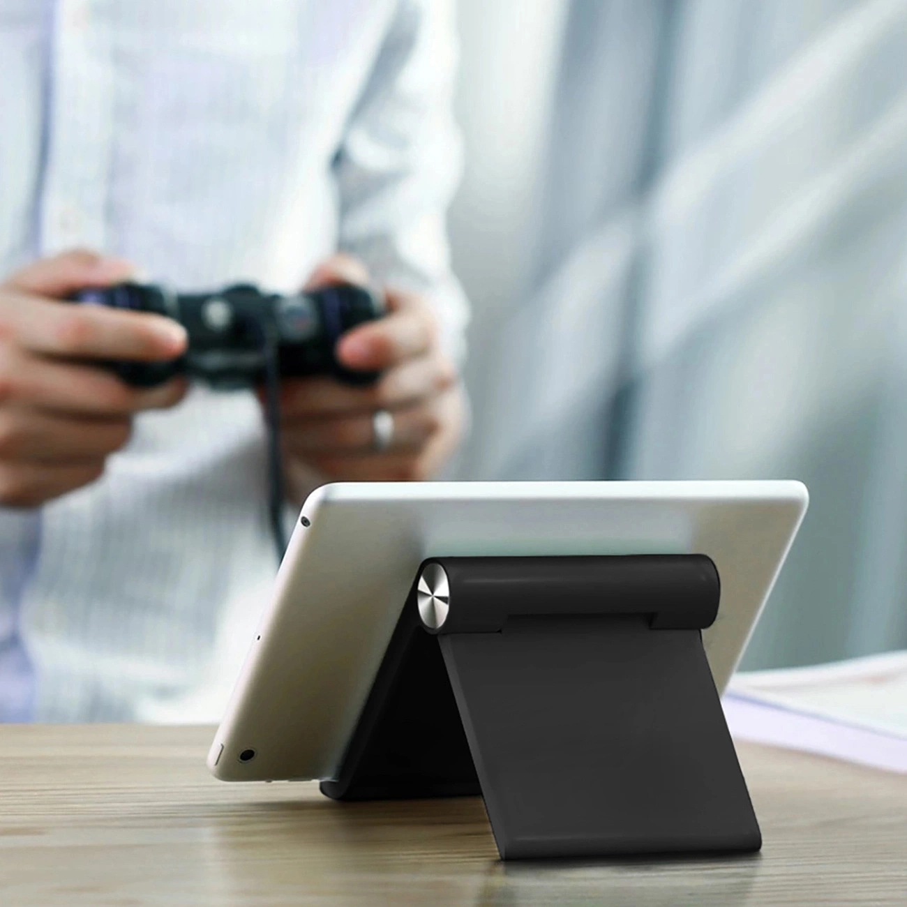 A person plays on a tablet resting on a Ugreen LP115 desk stand