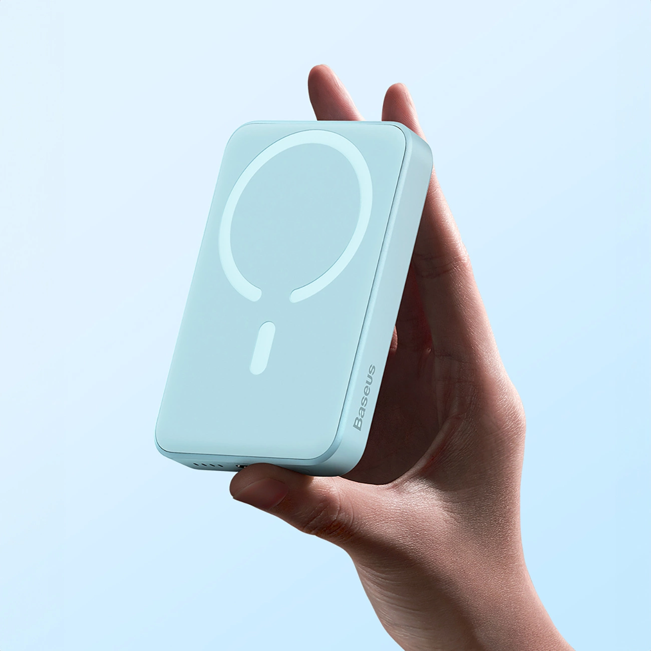 Baseus Magnetic Mini induction powerbank in the hand, facing upwards. The device shows an induction module