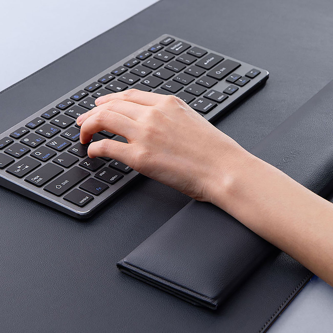 A hand typing on a keyboard on the Baseus MagPro Series II mat