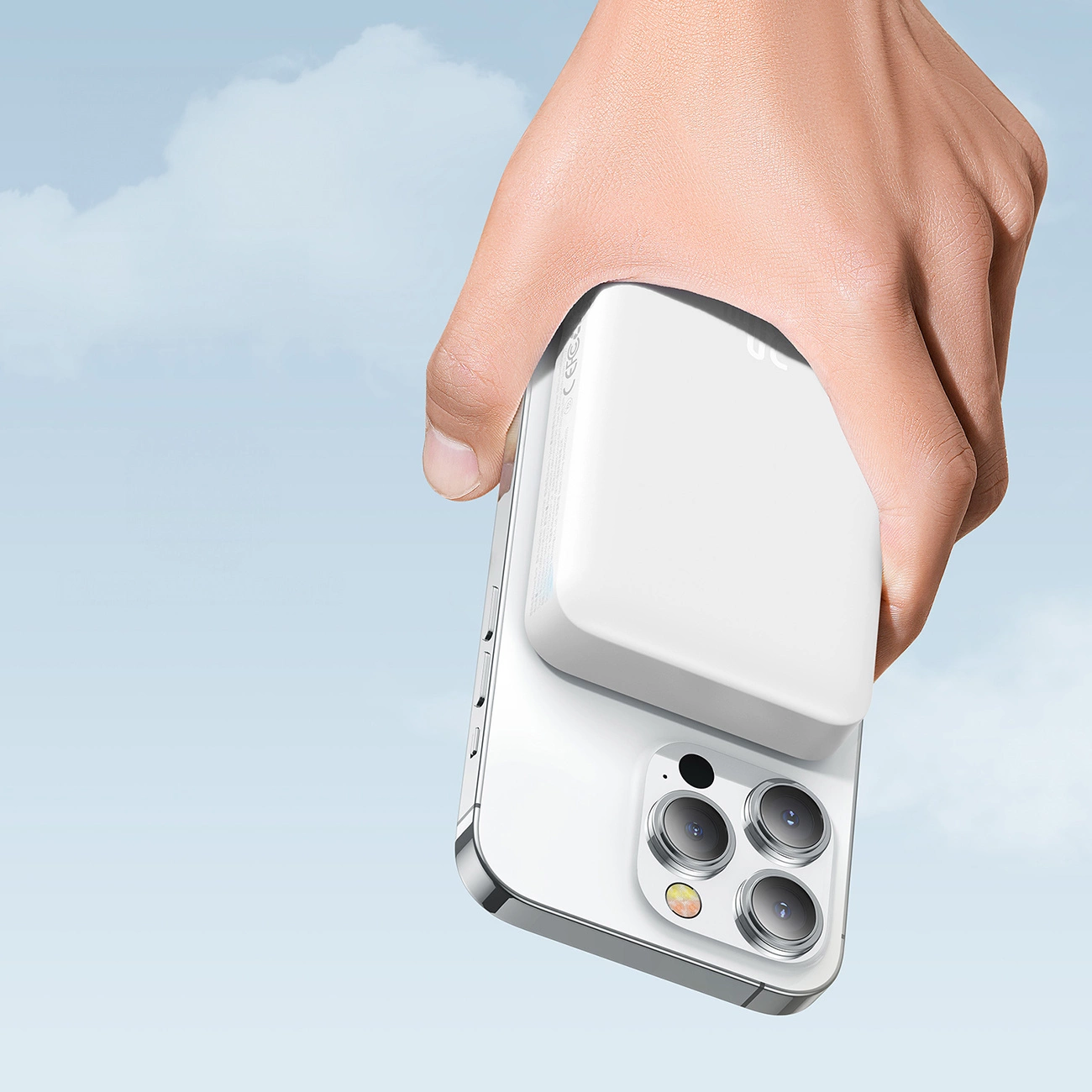 A hand holding a phone with a Baseus Magnetic Mini induction Powerbank 10000mAh 30W attached against the background of clouds