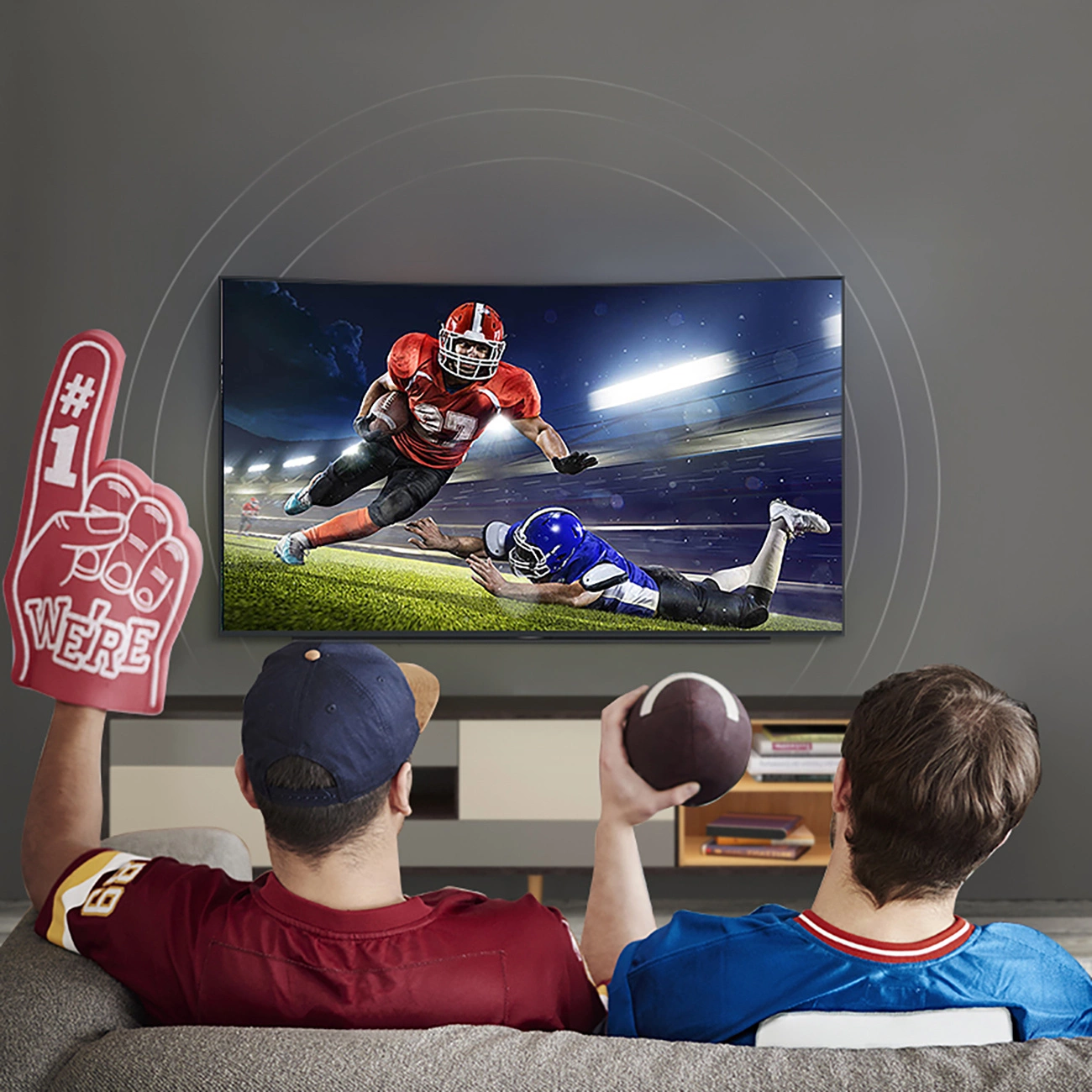 Two men watch American football on a TV that is connected to a home theater using a Ugreen AV122 optical cable.
