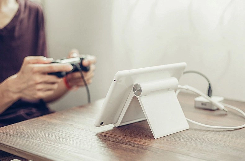 A woman plays on a tablet resting on a Ugreen LP115 desk stand