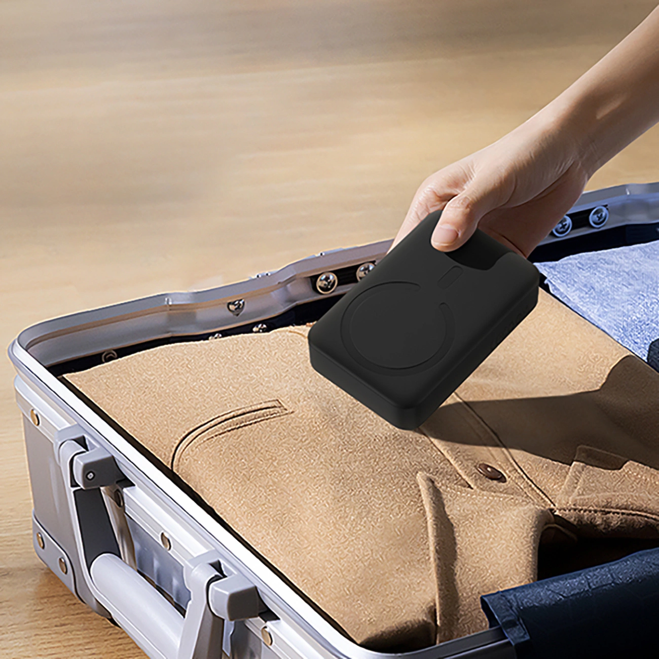 Osoba wkłada Powerbank Baseus Magnetic Mini indukcyjny 10000mAh 30W do walizki z ubraniami