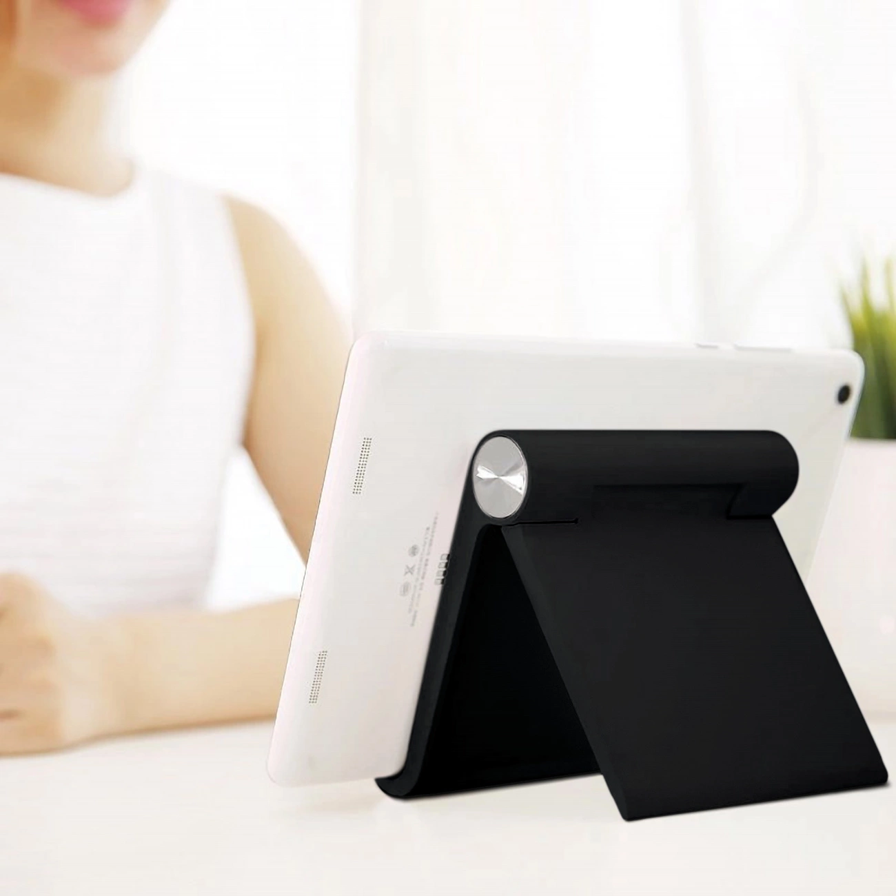 A woman watches a movie on a tablet leaning on the Ugreen LP115 desk stand