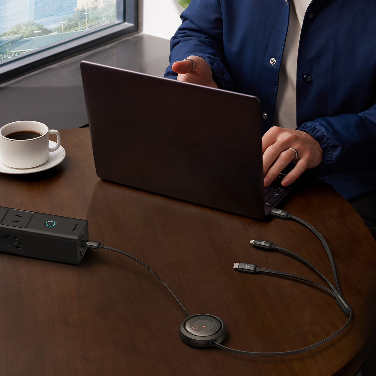 A man using a laptop charged with a Baseus Free2Draw retractable cable