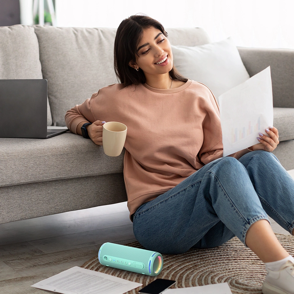 Woman sitting on the floor listening to music from Tronsmart T7 Lite wireless speaker