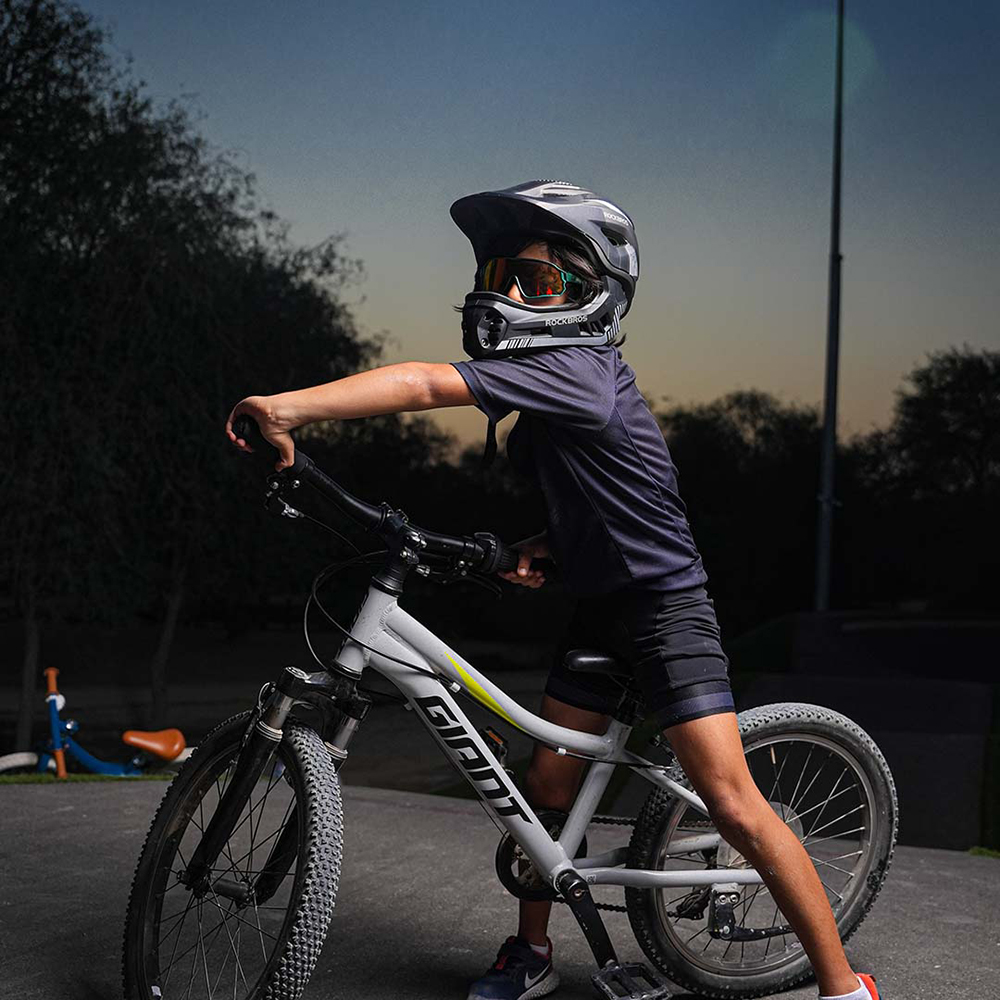 A boy wearing a Rockbros TT-32SBTG-L bicycle helmet with a detachable chinbar