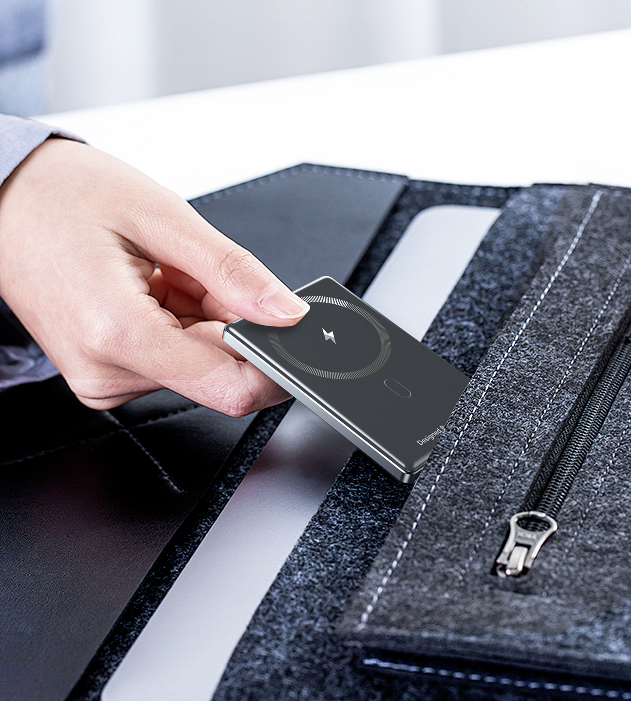 A hand placing the Choetech B738 Super Slim power bank into the pocket of a laptop bag.