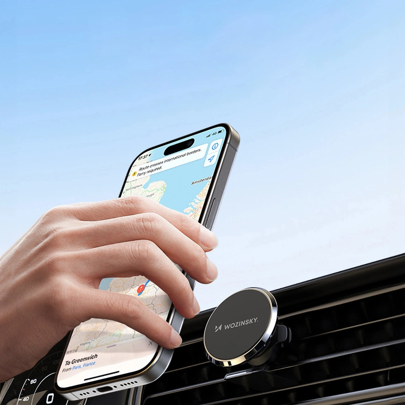 A hand placing an iPhone on a Wozinsky WUMKO magnetic car holder mounted on a car's air vent
