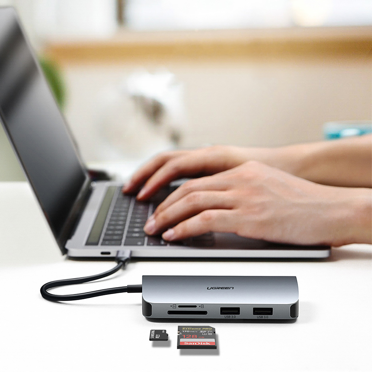 Hands typing on the keyboard of a laptop to which the Ugreen CM179 9in1 adapter is connected