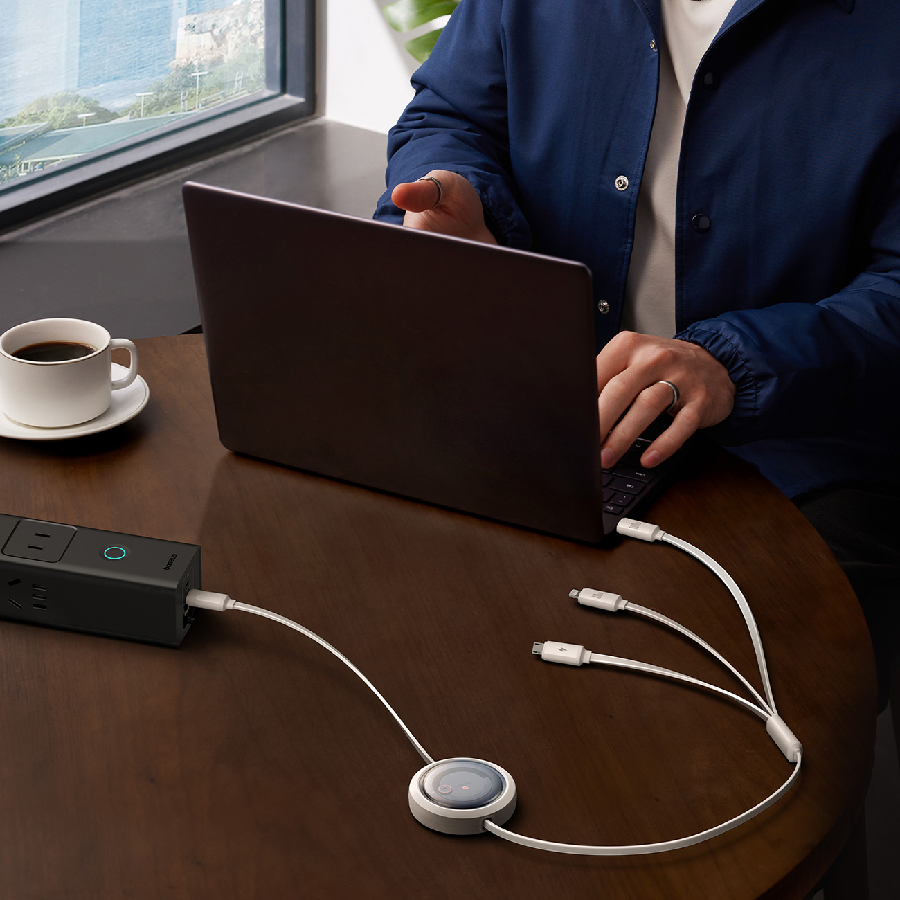 A man using a laptop charged with a Baseus Free2Draw retractable cable